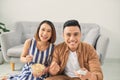 Shot of a cheeful young Asian couple watching television at home