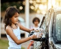 Getting the car nice and clean. Shot of a cheerful little girl washing her parents car outside during the day. Royalty Free Stock Photo