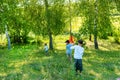 Children walk in a field on clear spring or a summer day. They catch butterflies or insects with a butterfly net. Happy childhood