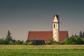 Shot of a church with a tower standing at the end of a greenfield