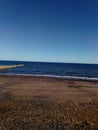 A shot of a clear summers sky over a deep blue ocean lapping ashore a pebbley beach, Dawlish, Devon, UK Royalty Free Stock Photo