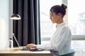 Concentrated beautiful businesswoman working with her laptop on the desk at the hotel room Royalty Free Stock Photo