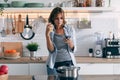 Concentrated mature woman using her mobile phone while drinking a cup of coffee at home