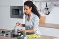 Concentrated young african american woman cooking healthy food in casserole in the kitchen at home