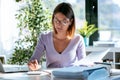 Concentrated young business woman working with calculator while consulting some documents in the office at home Royalty Free Stock Photo