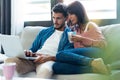 Confident beautiful couple using computer while sitting on the couch at home Royalty Free Stock Photo