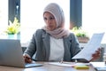 Confident young arabic business woman wearing hijab while working with laptop sitting in the office Royalty Free Stock Photo