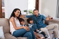 Its movie time for the whole family. Shot of a couple watching something on the television with their two young kids. Royalty Free Stock Photo