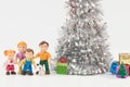 Shot of a cute doll family and small gift boxes under the lush silver Christmas tree Royalty Free Stock Photo