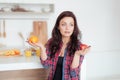 Shot of a dark haired caucasian woman comparing apples to oranges Royalty Free Stock Photo