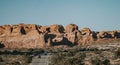 Shot of dry desert stones with a highway leading to it surrounded by some grass on a sunny day