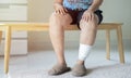 Shot of elder woman sitting on wooden chiar with injured leg. Wounds at the legs Royalty Free Stock Photo