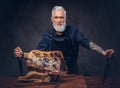 Old butcher cutting huge meat piece on wooden table