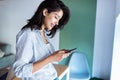 Elegant young business woman sending a phone message while standing in the office Royalty Free Stock Photo