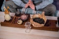 Shot without a face. A man meditates in front of a table with a full set of items for the tea ceremony, bamboo tray and