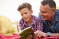 Books are gifts you can open again and again. Shot of a father and son reading a book together in a park. Royalty Free Stock Photo