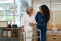Shot of female caregiver is teaching senior woman to walk with walker. Assistance, rehabilitation and health Royalty Free Stock Photo