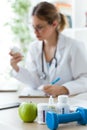 Female dietician holding a nutritional supplement while writing the properties in the consultation.