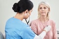 Let me take a listen. Shot of a female doctor examining a patient with a stethoscope. Royalty Free Stock Photo