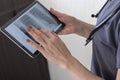 Shot of the female doctor in uniform against the white wall studying x-ray image of the lungs on the tablet. Healthcare Royalty Free Stock Photo