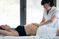 Female physiotherapist massaging tummy on pregnant woman in spa center