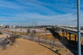 A shot of a freeway filled with cars and Semi trucks and tall power line poles along the highway with yellow winter grass