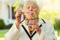 Shes on a playdate with her inner child. Shot of a fun-loving senior woman blowing bubbles outside on a sunny day. Royalty Free Stock Photo