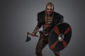 Aggressive viking with shield and axe dressed in black fur