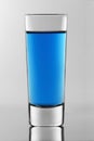 The shot glass with blue neon cocktail inside.