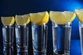 Shot glasses of vodka with lemon slices on blue background Royalty Free Stock Photo