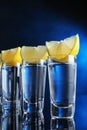 Shot glasses of vodka with lemon slices on blue background Royalty Free Stock Photo