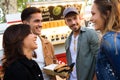 Group of attractive young friends talking while visiting eat market in the street.