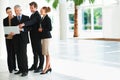 Making business happen. Shot of a group of businesspeople talking over a laptop while standing in an office lobby. Royalty Free Stock Photo