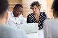 Group of intelligent young businesspeople working with laptop on coworking place