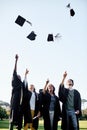 The rewards are all worth the effort. Shot of a group of students throwing their hats in the air on graduation day. Royalty Free Stock Photo