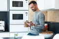 Handsome mature business man eating take away noodles while using smartphone in the kitchen at home Royalty Free Stock Photo