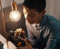 Bright minds come up with bright ideas. Shot of a handsome young boy building a robotic toy car at home.
