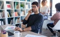 Handsome young entrepreneur talking on mobile phone while working with laptop in the office Royalty Free Stock Photo