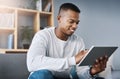 Just having a quick browse online. Shot of a handsome young man using his digital tablet while sitting on a sofa at home Royalty Free Stock Photo