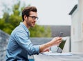 Keeping all his connections around. Shot of a handsome young man using a laptop and cellphone outdoors. Royalty Free Stock Photo