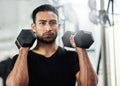 Im working hard to achieve my fitness goals. Shot of a handsome young man working out with dumbbells at the gym. Royalty Free Stock Photo
