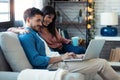 Happy beautiful couple using computer while sitting on the couch at home Royalty Free Stock Photo