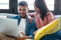 Happy beautiful couple using computer while sitting on the couch at home Royalty Free Stock Photo