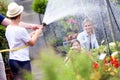 Happy boy playing with hose and wetting his mother and sister. Royalty Free Stock Photo