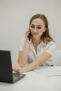 Shot happy businesswoman sitting at desk behind her laptop and talking with somebody on her mobile phone while working from home. Royalty Free Stock Photo