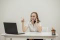 Shot happy businesswoman sitting at desk behind her laptop and talking with somebody on her mobile phone while working from home. Royalty Free Stock Photo