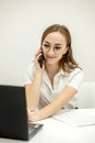 Shot happy businesswoman sitting at desk behind her laptop and talking with somebody on her mobile phone while working from home. Royalty Free Stock Photo