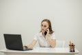 Shot happy businesswoman sitting at desk behind her laptop and talking with somebody on her mobile phone while working Royalty Free Stock Photo