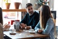 Happy friends group eating burgers while talking about work using digital tablet sitting in restaurant Royalty Free Stock Photo