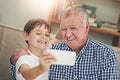 Are you ready, Gramps. Shot of a happy grandfather and his grandson taking a selfie together on a mobile phone at home. Royalty Free Stock Photo